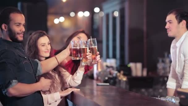 Alegre compañía de chicas y un chico en el bar levanta un vaso de cerveza — Vídeos de Stock