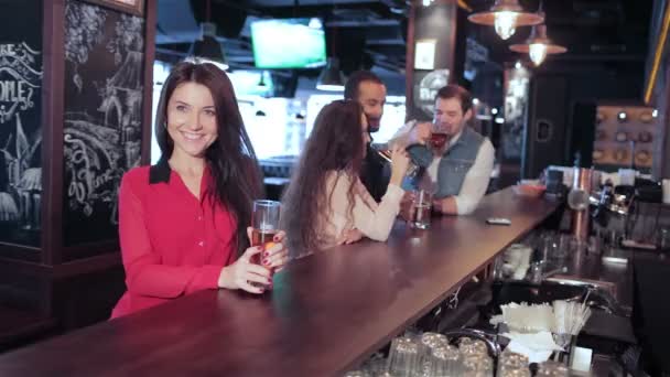Девушка с бокалом пива в баре приветствует друзей — стоковое видео