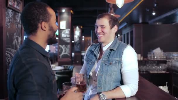 Zwei schwule Freunde an der Bar mit einem Bier und lächeln dann in die Kamera — Stockvideo