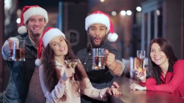 Üç arkadaş Noel Baba şapkaları ve barda bir bardak bira ile kız