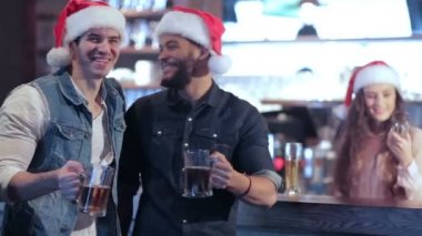 İki arkadaş Noel Baba şapkaları ve barda bir bardak bira ile kız