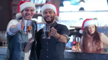 Noel Baba şapkaları ve bir bira ile barın arkasındaki kız iki arkadaş kendi gözlük kaldırdı