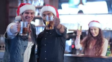 İki arkadaş Noel Baba şapkaları ve kız barın arkasında olduğunu memnuniyetle yeni arkadaşlar