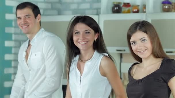 Трое друзей готовят себе здоровый ужин и улыбаются прямо перед камерой — стоковое видео