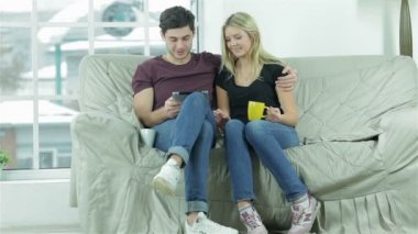 Şirin çift bir kucaklama içinde oturan ve bir tablet ile eğlenin