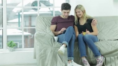 Şirin çift bir kucaklama içinde oturan ve bir tablet ile eğlenin