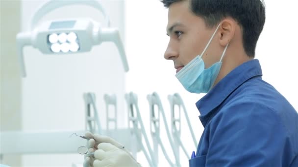 Дантист держит в руках стоматологический инструмент — стоковое видео