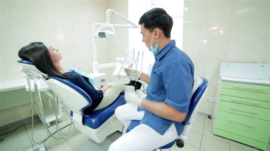 Diş hekimi diş sandalyede oturan hasta için daha yakın ve ona gülümseyerek konuşuyor