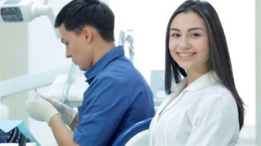 Diş hekimi diş ve asistan kız dişler gülümseme ve başparmak yukarıya ele alır