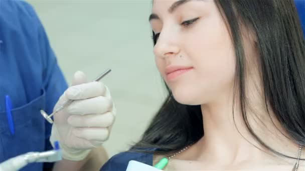 Крупный план лица девушки, которая смотрит на стоматолога с инструментом в руках — стоковое видео