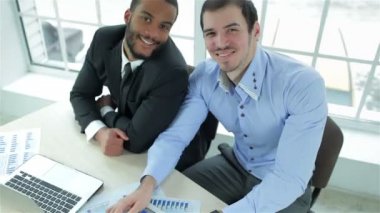 Gülümseyen ve parmağını gösterilen iki başarılı iş adamı