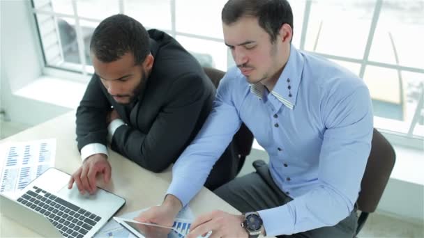 Dos hombres de negocios serios trabajando en una tableta y un portátil — Vídeos de Stock