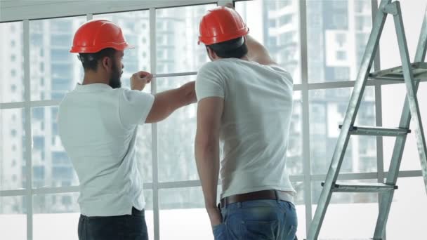 Dos trabajadores hacen mediciones de ventanas y reparaciones — Vídeos de Stock