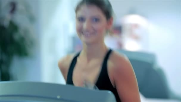 Jeune fille mignonne courant dans la salle de gym souriant et regardant la caméra — Video