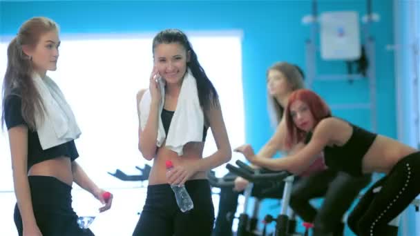 Chica atleta recibe una llamada mientras sus amigos participan en deportes y pedaleo — Vídeos de Stock