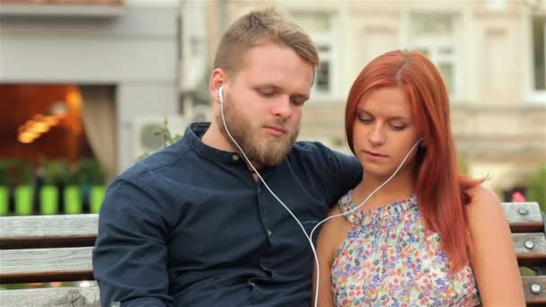 Casal partilha de música num parque urbano — Vídeo de Stock