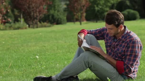 Ember olvasás közben ül a fűben — Stock videók