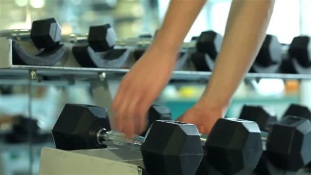 Close-up of hands of a young man who takes to perform dumbbell — Stock Video