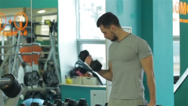 Genç adam bir ayna yansıması dumbbells ile bir program yapıyor — Stok video