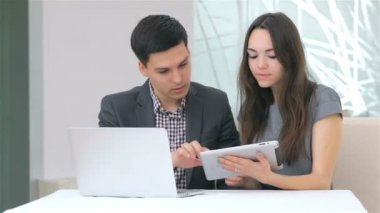 Genç çekici iş erkek ve kadın harmanlama veri tablet üzerinde tartışıyor