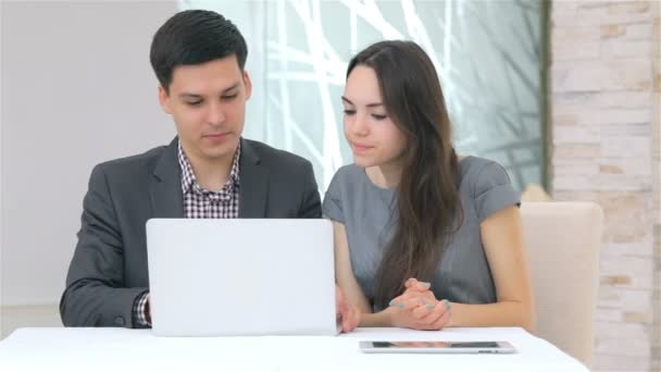 Joven atractivo hombre y mujer de negocios discutiendo la comparación de los datos en el ordenador portátil — Vídeo de stock