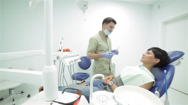 El dentista acude al paciente en la silla y comienza a inspeccionar los dientes — Vídeo de stock