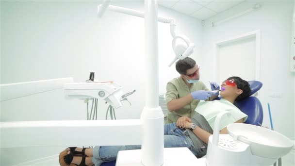 Dentista brilla sello fotopolímero ultravioleta en la fijación de ella — Vídeos de Stock