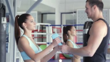 Genç çekici kadın atlet onun Koç dumbbells elinden alır