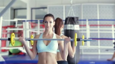 Kız atlet barbell ile egzersizleri yapıyor onun fitness eğitmeni araya geldi.