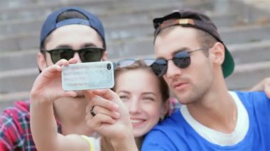 Arkadaşlarının merdivenlerinde oturan neşeli kız selfie yapıyor