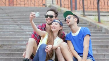 Arkadaşlarının merdivenlerinde oturan neşeli kız selfie yapıyor