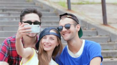 Arkadaşlarının merdivenlerinde oturan neşeli kız selfie yapıyor