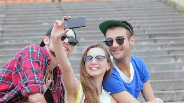 Fröhliches Mädchen, das auf den Stufen seiner Freunde sitzt, macht Selfie — Stockvideo