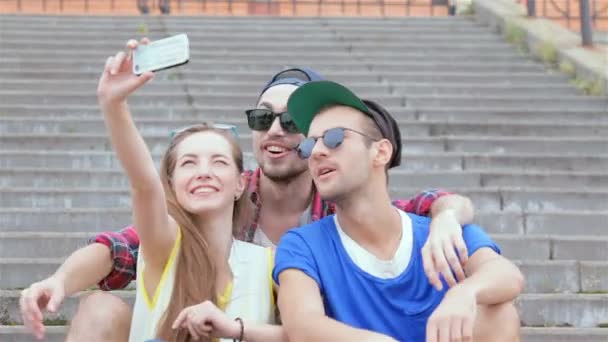 Chica alegre sentado en los pasos de sus amigos hace selfie — Vídeos de Stock