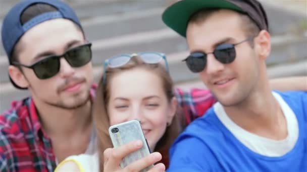 Cheerful girl sitting on the steps of his friends makes selfie — Stock Video