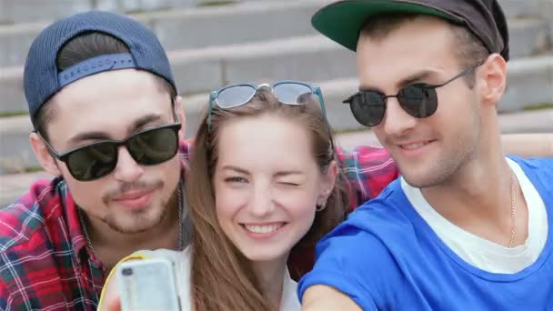 Cheerful girl sitting on the steps of his friends makes selfie — Stock Video