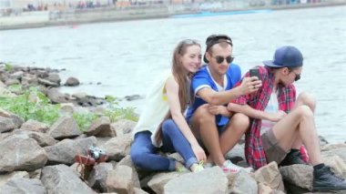 Üç arkadaş oturup nehre gülüyorve birbirlerinin resimleri