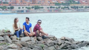 Nehir kıyısındaki kayalıklarda oturan ve gülen üç arkadaş