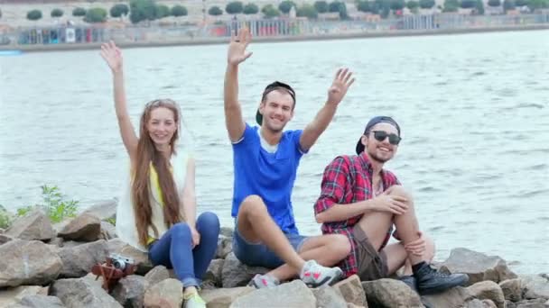 Tři přátelé sedí a mávají na kameře — Stock video