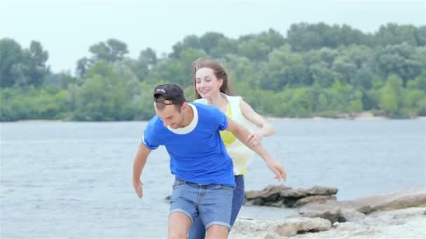 Girl guy jumped on his back and they run on the beach slow motion — Stock Video