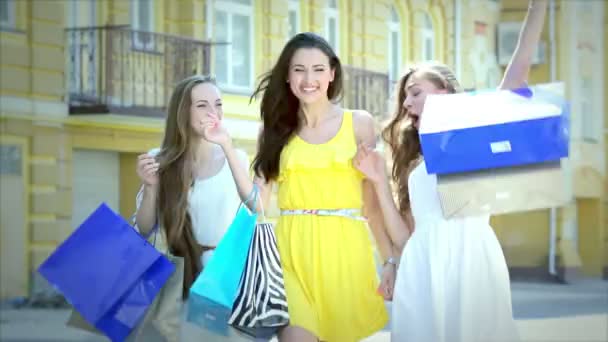 Tre ragazze felici passeggiando lungo le boutique alla moda con pacchetti shopping — Video Stock