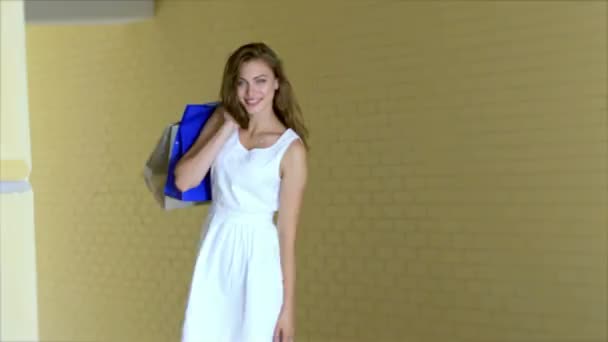 Mladý veselý dívka-shopaholic pózování s nákupy — Stock video