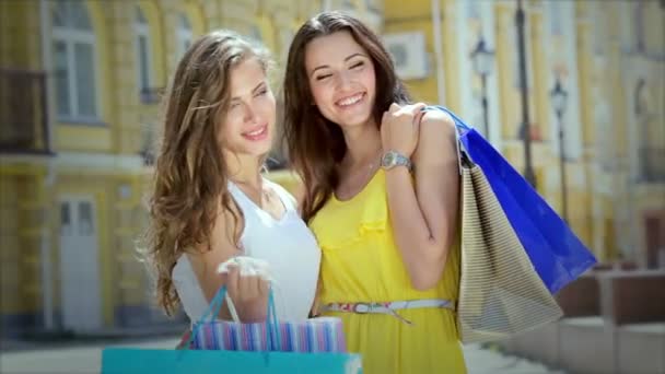 Dos niñas agradable y posando mientras sostiene bolsas de compras con la moda — Vídeos de Stock