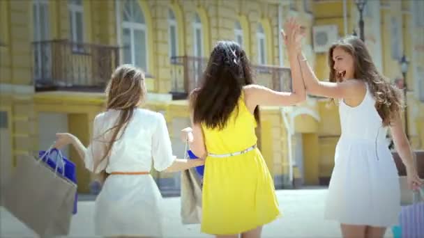 Три милые девушки идут рука об руку во время шоппинга — стоковое видео