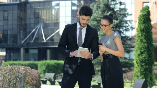 Obchodní dvojice stojí pohromadě, pracují na tabletu a usmívají se — Stock video