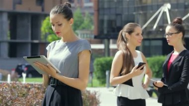 İş ortaklarının arka planında tablet üzerinde çalışan iş kadını