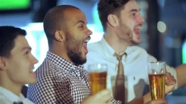 Erkek taraftarlar ellerini sallayarak ve Tv'de futbol izlerken ve bira içmek