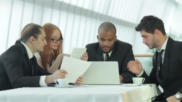 Vier lachende succesvolle zakenlui zittend aan tafel in kantoor — Stockvideo