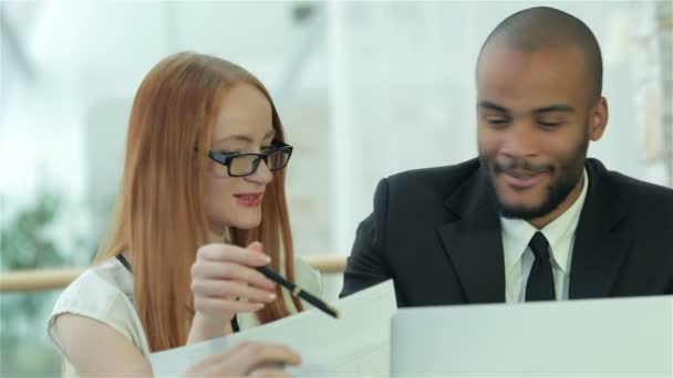 Sorrindo empresários bem sucedidos sentados à mesa no escritório enquanto discutem — Vídeo de Stock