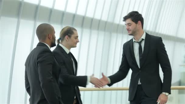 Четыре улыбчивых успешных бизнесмена пожимают друг другу руки — стоковое видео